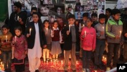 Pakistani children take part in a candlelight vigil to mark the second anniversary of the attack on a Peshawar school in 2014, in Lahore, Pakistan, Dec. 16, 2016. 
