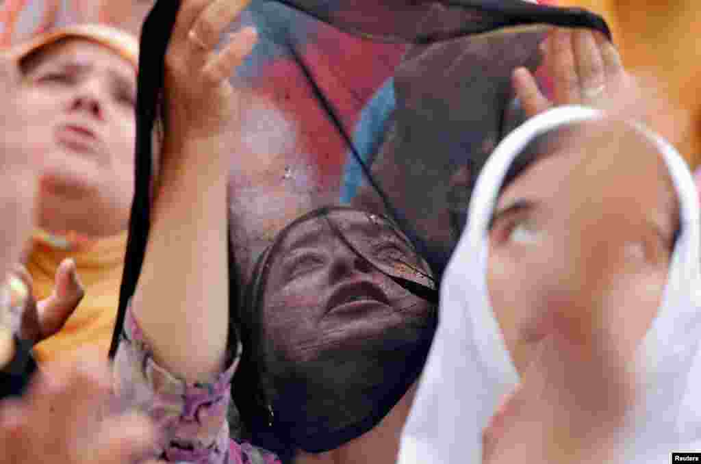 Muslim women react upon seeing a relic, believed to be a hair from the beard of Prophet Mohammad, displayed to devotees on the death anniversary of Hazrat Ali, son-in-law of Prophet Mohammad, at Hazratbal shrine during the holy month of Ramadan in Srinaga, Indian-controlled Kashmir.