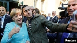 FILE - Syrian refugee Anas Modamani takes a selfie with German Chancellor Angela Merkel outside a refugee camp near the Federal Office for Migration and Refugees after registration at Berlin's Spandau district, Germany, Sept. 10, 2015. 