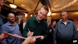 FILE - Democratic Congressional candidate Jared Golden, left, autographs a campaign sign as he and his supporters wait for election results in the 2nd Congressional District election in Lewiston, Maine, Nov. 6, 2018.