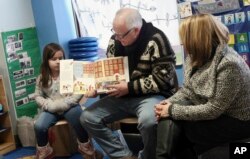 Gov. Tim Walz, top, reads a book to children at People Helping People, a shelter for families experiencing homelessness amid extreme cold weather conditions in Minnesota, Jan. 29, 2019, in Minneapolis, accompanied by Lt. Gov. Peggy Flanagan, right.