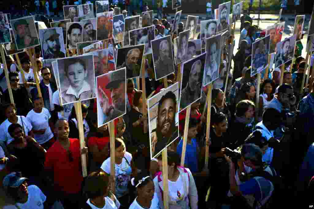 People hold photos of Cuba&#39;s late leader Fidel Castro in a march to commemorate one year since Castro was buried, in Santiago.