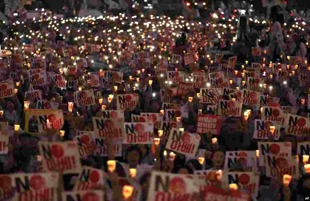 Protesters hold candles and signs during a rally in downtown Seoul, denouncing Japanese Prime Minister Shinzo Abe and also demanding the South Korean government to abolish the General Security of Military Information Agreement, or GSOMIA, an intelligence-sharing agreement between the two countries.