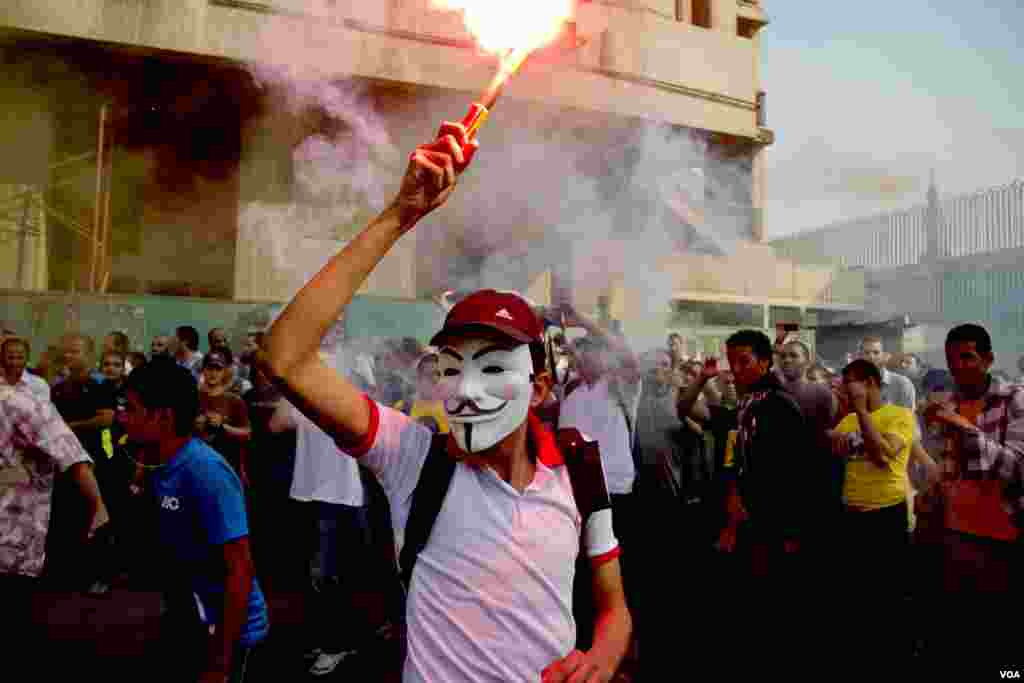 An anti-coup protester wearing a Guy Fawkes mask hold a flare during a demonstration in Cairo, Oct. 6, 2013. (H. Elrasam for VOA)