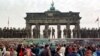 FILE - East Berlin border guards stand atop the Berlin Wall in front of the Brandeburg Gate on November 11, 1989.