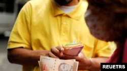 Una mujer paga un pasaje de autobús con billetes de 50.000 bolívares, la moneda local, en Caracas, el 16 de marzo de 2021. Foto: Reuters.