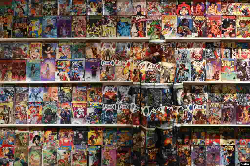 Liu Bolin, a Chinese artist, blends himself into the background in front of a shelf lined with comic books as part of a series of performances in Caracas, Venezuela, Nov. 2, 2013.