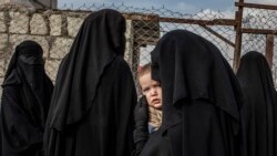 A Russian woman carries her child while queuing at a makeshift hospital in The Annex at Al-Hol refugee camp in northern Syria on November 14, 2019.