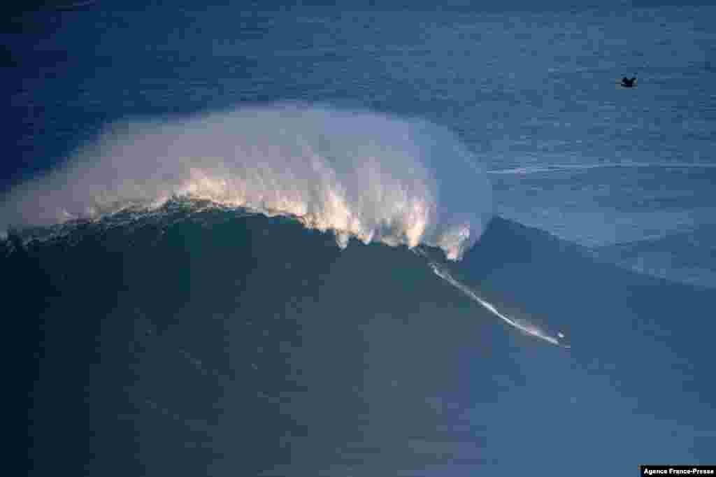 A surfer rides a wave during a big wave surfing session at Praia do Norte in Nazare, Portugal, Jan. 8, 2022.