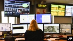 FILE- A dispatcher works at a desk station with a variety of screens used by those who take 911 emergency calls in Roswell, Ga., March 15, 2018. The Roswell call center is one of the few in the United States that accepts text messages.