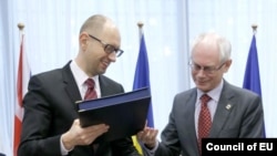 Thủ tướng lâm thời Ukraina Arsenyi Yatsenyuk (trái) và Chủ tịch Hội đồng châu Âu Herman Van Rompuy trao đổi tài liệu tại lễ ký hiệp ước ở Brussels, 21/3/2014.