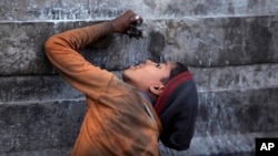 An Indian ragpicker boy drinks water from a tap at an automobile yard on the outskirts of Jammu, India.