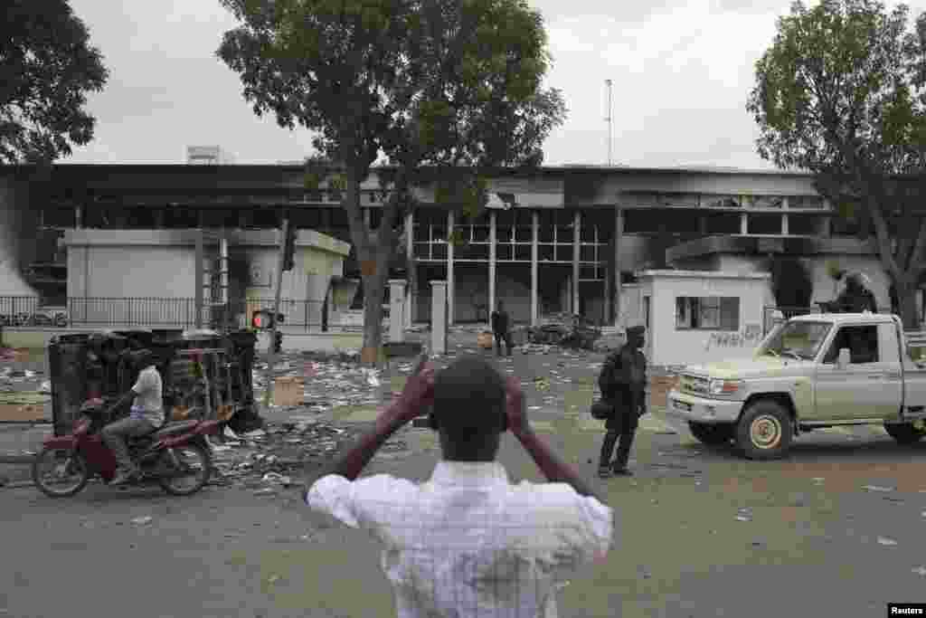 A man takes a picture of the burned parliament building in Ouagadougou, capital of Burkina Faso, October 31, 2014. General Honore Traore, head of Burkina Faso's armed forces, took power on Friday after President Blaise Compaore resigned amid mass protests