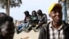 Des journaliers migrants africains à la recherche de petits emplois attendent sous un pont dans la capitale libyenne Tripoli pour être embauchés par des employeurs potentiels, le 6 mars 2021.