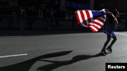 A woman holds an American flag as she skates up 5th Avenue during a Veterans Day parade in New York.