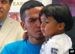 Javier Garrido Martinez holds his 4-year-old son during a news conference in New York, Wednesday, July 11, 2018.