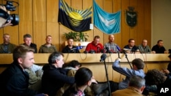 Vyacheslav Ponomaryov, the self-proclaimed mayor of Slovyansk, fourth from left, is flanked by a group of foreign military observers being held by Ponomaryov's group during a press conference in city hall, Slovyansk, eastern Ukraine, April 27, 2014.