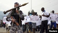 A Burundian soldier walks infront of residents during a demonstration against the Rwandan government in Burundi's capital Bujumbura, Feb. 20, 2016. 