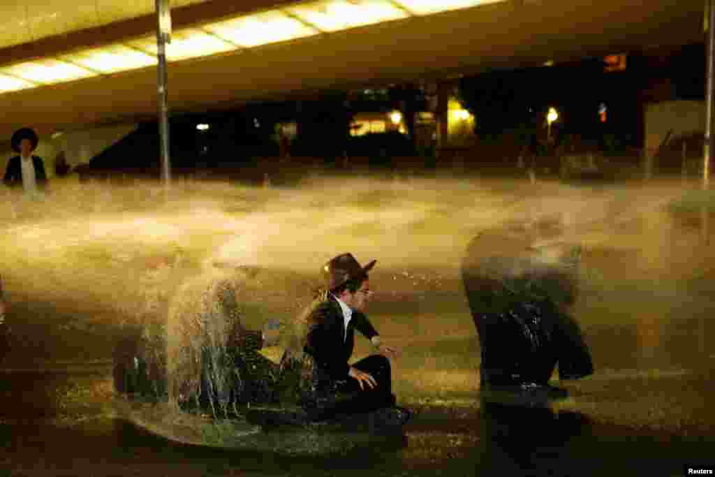 Israeli police use water cannons to disperse ultra-Orthodox Jewish men during a protest against the detention of a member of their community who refuses to serve in the Israeli army, in Jerusalem.