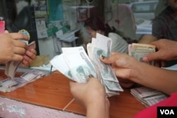 FILE - Cambodians count Cambodia's currency Riel at a local Money Exchange counter, in Phnom Penh, on April 7, 2016. ( Leng Len/VOA Khmer)