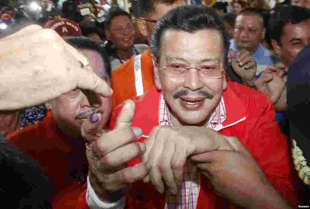 A supporter greets former Philippine President Joseph Estrada after Estrada cast his vote inside a precinct poll at a school in Manila May 13, 2013. 