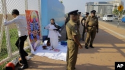 FILE - Sandya Ekneligoda, in black scarf, prepares ritualistic offerings for Hindu deity Kali seeking her blessings to find her missing husband, journalist Prageeth Ekneligoda, outside the office of the President in Colombo, Sri Lanka, Jan. 24, 2019.