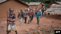 FILE - Anti-Balaka combatants patrol in the parish of Gambo, southeastern Central African Republic, Aug. 16, 2017.