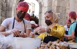 Relawan dari organisasi amal "Saed" menyiapkan makanan untuk dibagikan kepada orang-orang yang membutuhkan selama bulan suci Ramadhan, di Damaskus, Suriah, 23 April 2021. (Foto: REUTERS/Firas Makdesi)