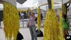 A mother and her daughter tie yellow ribbons with messages for missing passengers and victims aboard the sunken ferry Sewol. (July 2014)
