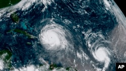 This Thursday, Sept. 7, 2017 satellite image made available by NOAA shows the eye of Hurricane Irma, left, just north of the island of Hispaniola, with Hurricane Jose, right, in the Atlantic Ocean. (NOAA via AP)