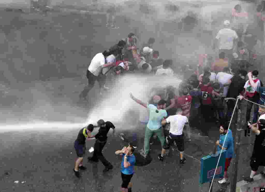 Lebanese activists are sprayed by riot police using water cannons during a protest against the ongoing trash crisis, in downtown Beirut, Aug. 23, 2015.