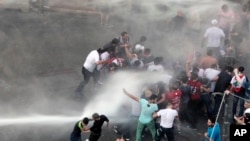Lebanese activists are sprayed by riot police using water cannons during a protest against the ongoing trash crisis, in downtown Beirut, Lebanon, Aug. 23, 2015.