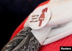 FILE - A badge reads "The power of labor aginst FGM" is seen on a volunteer during a conference on International Day of Zero Tolerance for Female Genital Mutilation in Cairo, Egypt, Feb. 6, 2018.