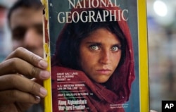Pakistan's Inam Khan, owner of a book shop shows a copy of a magazine with the photograph of Afghan refugee woman Sharbat Gulla, from his rare collection in Islamabad, Pakistan, Oct. 26, 2016.