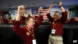 Engineers Kris Bruvold, left, and Sandy Krasner celebrate as the InSight lander touches down on Mars in the mission support area of the space flight operation facility at NASA's Jet Propulsion Laboratory in Pasadena, Calif., Nov. 26, 2018.