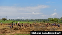 People work at a gold mining site in the village of Mawero, outside of Busia town, in eastern Uganda on Monday, Oct. 18, 2021. With schools closed, students work alongside adults, including some of their teachers, at the mine. (AP Photo/Nicholas Bamulanzeki)
