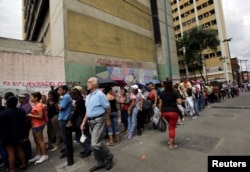 FILE - People stand in line as they wait to buy staple items and basic food along a sidewalk of a supermarket in Caracas, Venezuela, Sept. 8, 2016.