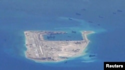FILE - Chinese dredging vessels are purportedly seen in the waters around Fiery Cross Reef in the disputed Spratly Islands in the South China Sea in this still image from video taken by a P-8A Poseidon surveillance aircraft provided by the United States Navy.