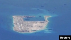 FILE - Chinese dredging vessels are purportedly seen in the waters around Fiery Cross Reef in the disputed Spratly Islands in the South China Sea in this still image from video taken by a P-8A Poseidon surveillance aircraft provided by the United States Navy.