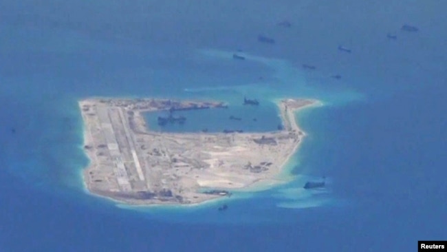 FILE - Chinese dredging vessels are purportedly seen in the waters around Fiery Cross Reef in the disputed Spratly Islands in the South China Sea in this still image from video taken by a P-8A Poseidon surveillance aircraft provided by the United States Navy.
