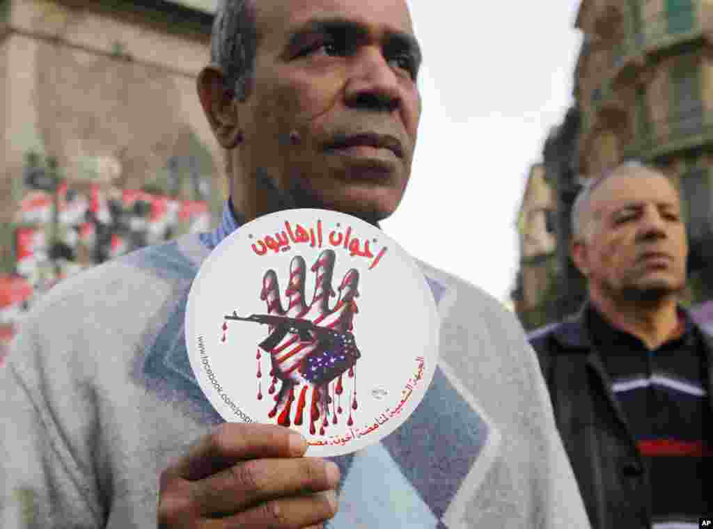 An activist holds a sign with an anti-terrorism picture and Arabic that reads &quot;terrorists brotherhood&quot; during an anti-terrorism demonstration in Cairo, Dec. 26, 2013. 