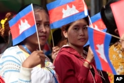 Garment workers welcome Prime Minister Hun Sen outside of Phnom Penh, Cambodia, Wednesday, Aug. 30, 2017. Hun Sen is on a country-wide trip to visit the nation's factory workers to hear their hopes and concerns in person. (AP Photo/Heng Sinith)