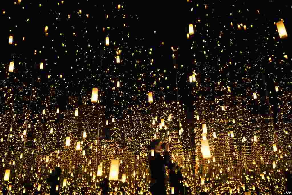 Uma mulher tira fotografias dentro de um espaço chamado Aftermath of Obliteration of Eternit, na ante-estreia da exposição Espelhos Infinitos de Yayoi Kusama no museu Hirshhorn em Washington, D.C., EUA. Fev. 21, 2017.