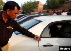 A policeman shows the media a bullet hole in the door of a car which belongs to journalist Hamid Mir, at a local hospital in Karachi, Apr. 19, 2014.