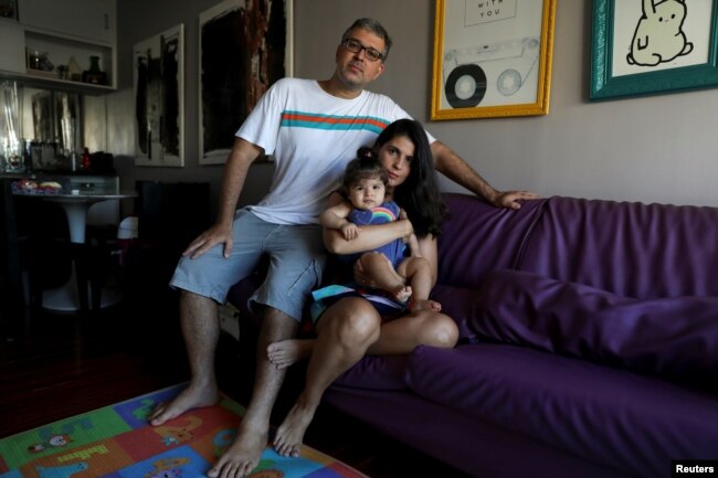 Tatiana Barcellos, 37, a civil servant for the Federal Prosecutor's Office, her eight-month-old daughter Alice, and her husband Marcelo Valenca, 39, a teacher at a navy school, pose for a photograph on the day Tatiana went back to work, at their home in Rio de Janeiro, Brazil, Jan. 28, 2019.