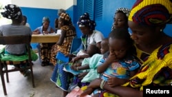 Women holding children wait for a medical examination at the health center in Gbangbegouine village, western Ivory Coast, July 4, 2013. 