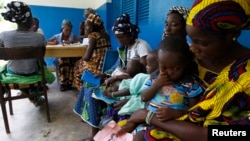 Women holding children wait for a medical examination at the health centre in Gbangbegouine village, western Ivory Coast, July 4, 2013. 