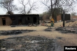 A woman carrying a child stands near burnt houses in the aftermath of what Nigerian authorities said was heavy fighting between security forces and Islamist militants in Baga, a fishing town on the shores of Lake Chad, April 21, 2013.