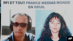 Pictures of French RFI journalists, Ghislaine Dupont, right, and Claude Verlon on a poster headed "RFI and all France Media World in Mourning" displayed in a window in Paris, Nov. 3, 2013. 