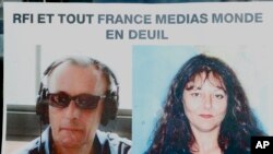 Photos de journalistes français de RFI, Ghislaine Dupont, à droite, et Claude Verlon sur une affiche intitulée «RFI et tous France Médias en deuil" affichée dans une fenêtre à Paris, le 3 novembre 2013. (AP Photo/Jacques Brinon)
